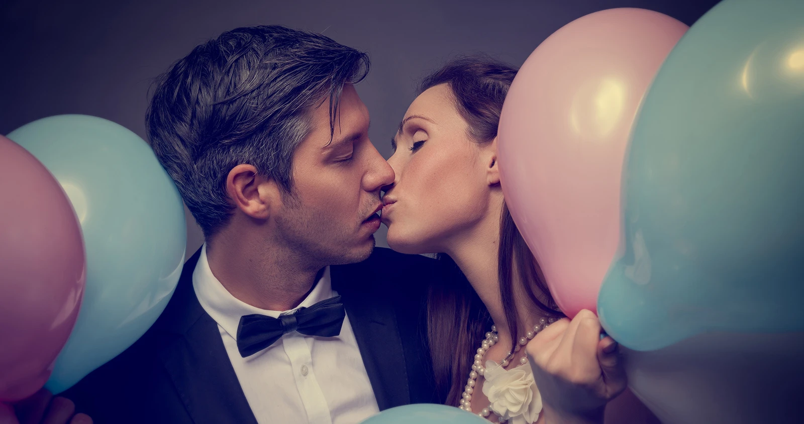 Jeunes mariés entourés de ballons s'embrassant devant notre photomaton