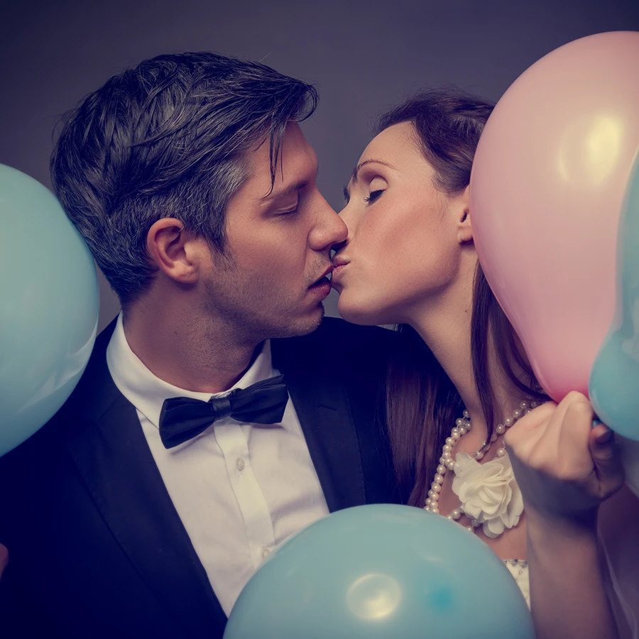 Jeunes mariés entourés de ballons s'embrassant devant notre photomaton